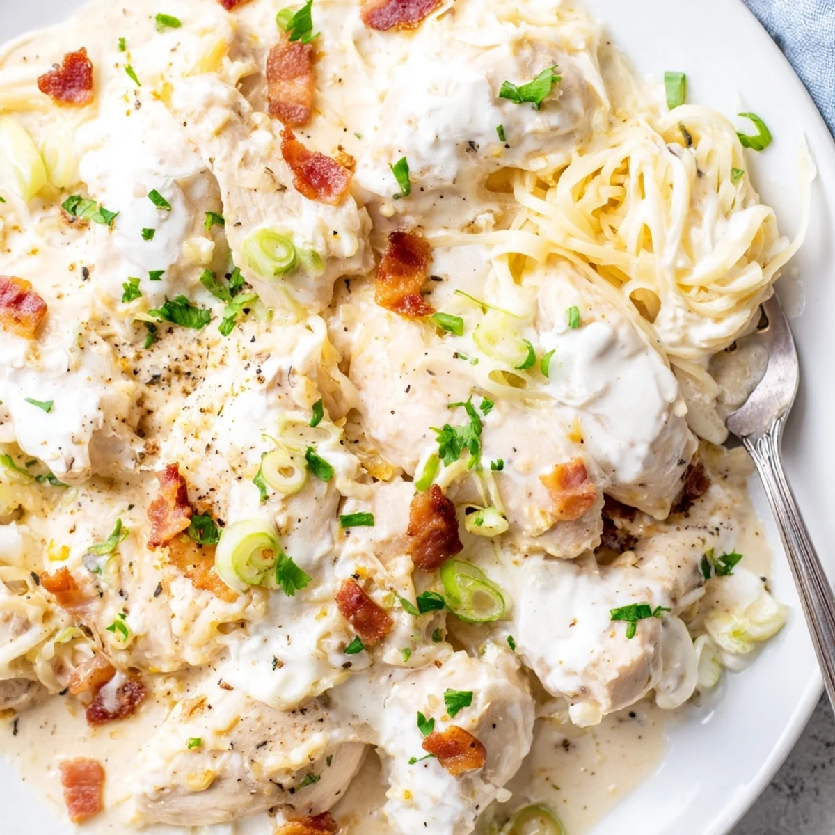 Golden cheesy Crockpot Million Dollar Chicken topped with crispy bacon crumbles and fresh parsley
