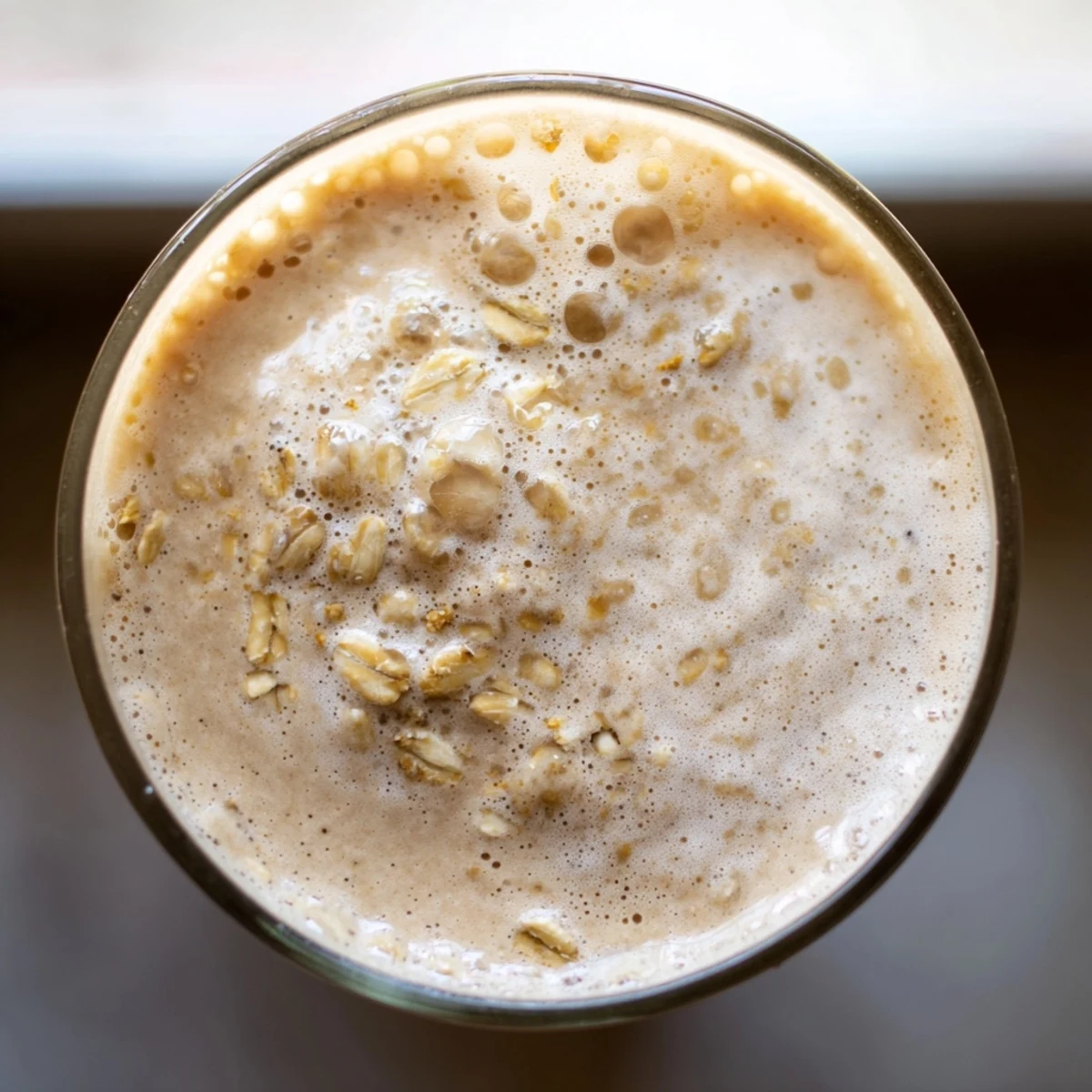 Creamy coffee smoothie in a glass with banana slices and ice cubes ready to serve