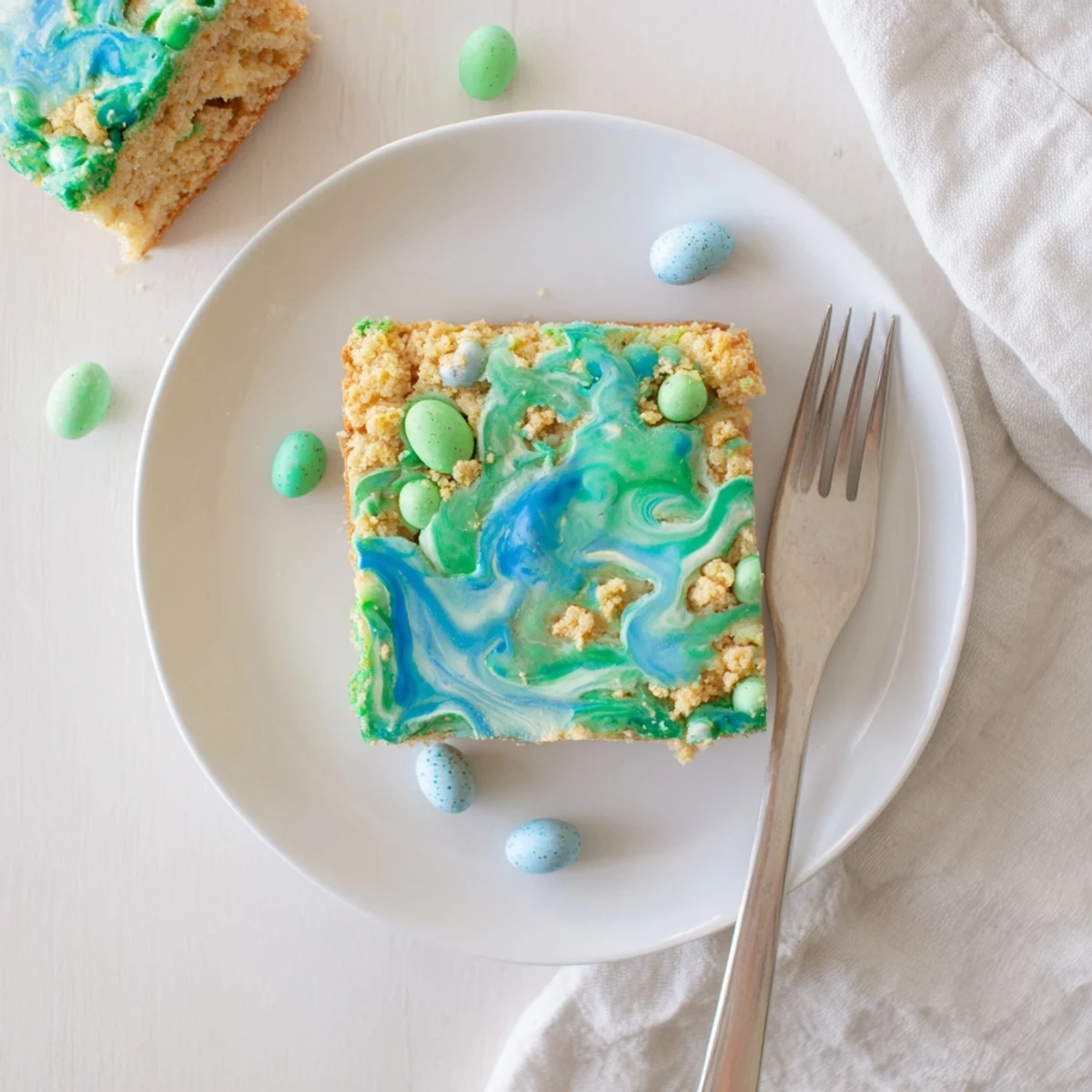 Tender vanilla Robin Egg Snack Cake studded with speckled malted candies on a cutting board