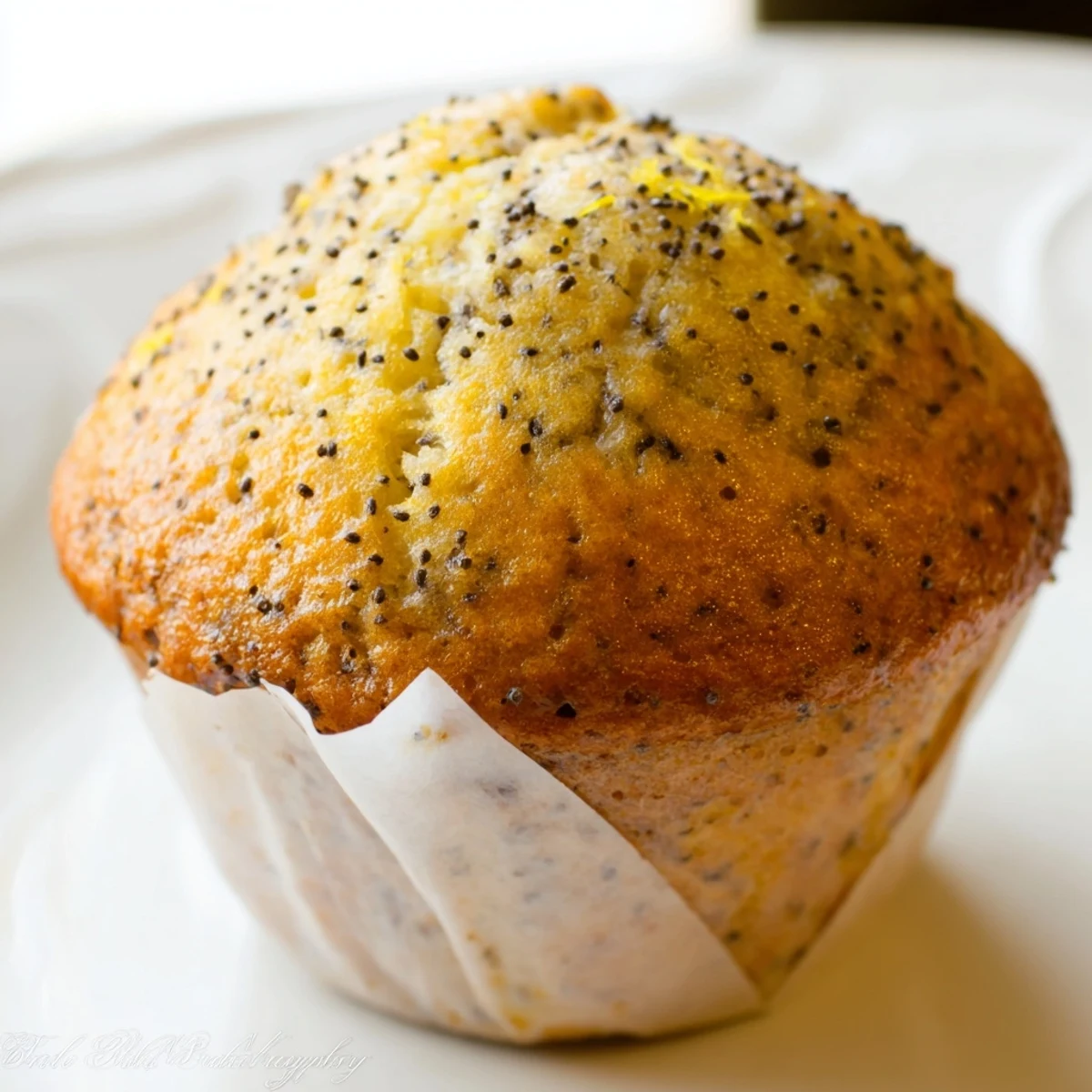 Moist lemon poppy seed muffins studded with speckled seeds beside a zesting grater