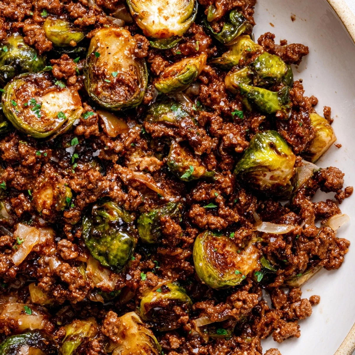 Golden caramelized ground beef and Brussels sprouts sizzling in a cast iron skillet