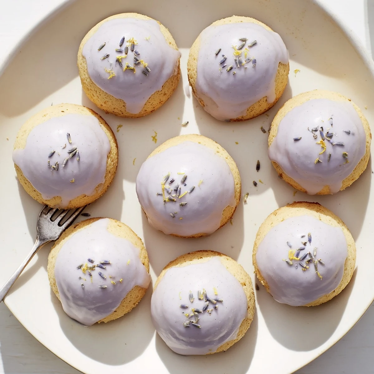 Mini lemon cakes with lavender glaze served on a dainty afternoon tea plate