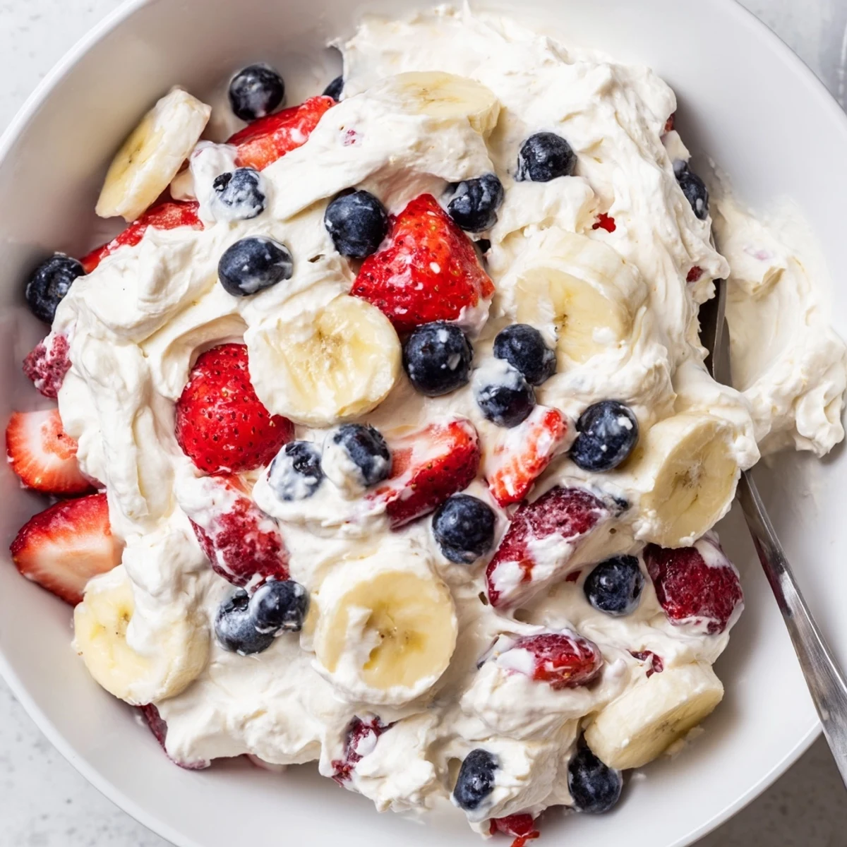 Chilled Red White And Blue Cheesecake Salad layered with bananas, tart lemony berries.