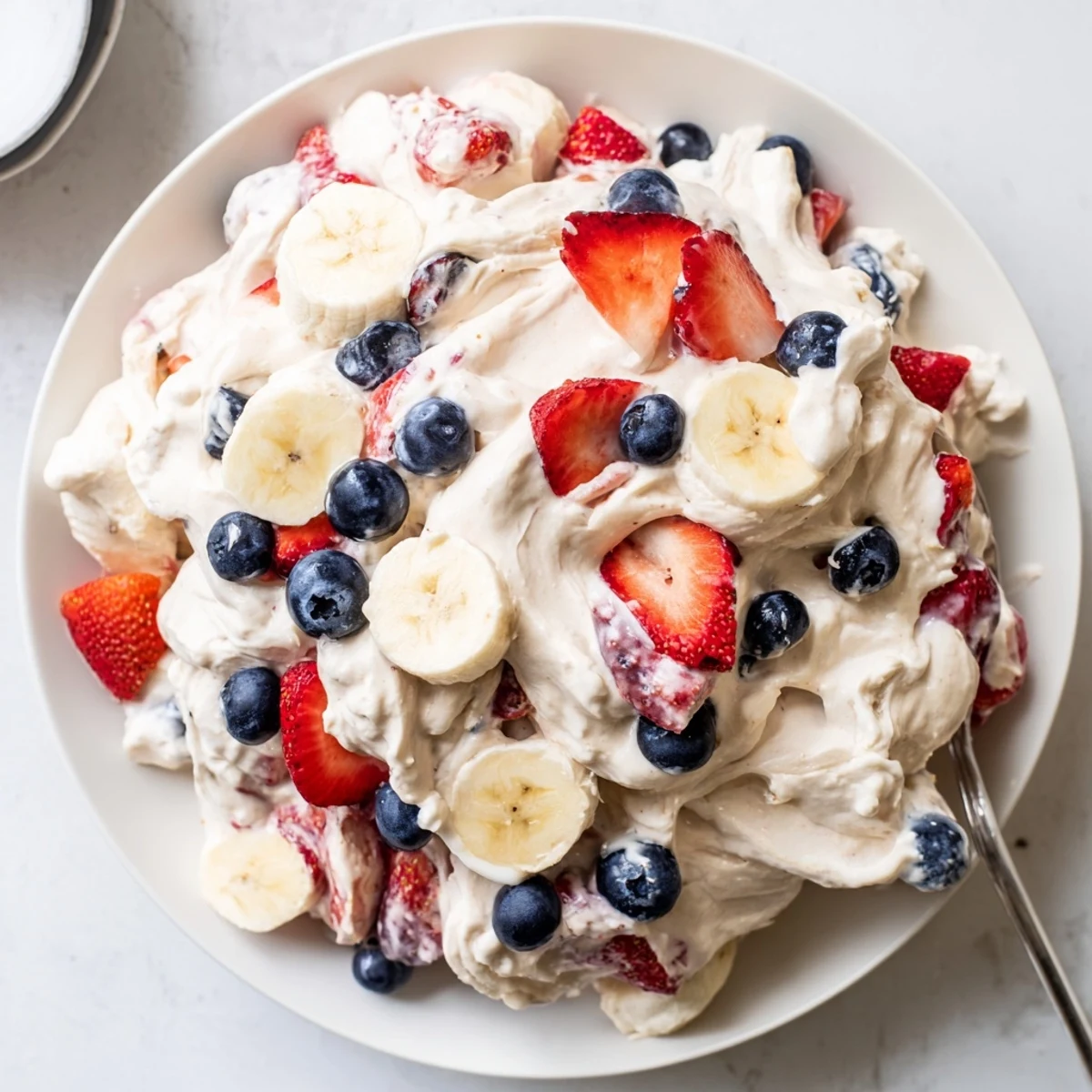 Patriotic Red White And Blue Cheesecake Salad scooped into bowls, cool and fluffy.
