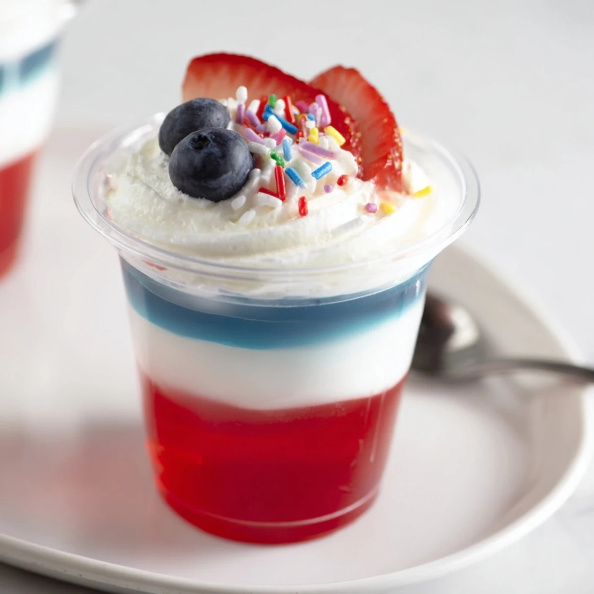 Red White And Blue Jello Cups show spoon-ready layers, creamy white middle visible.