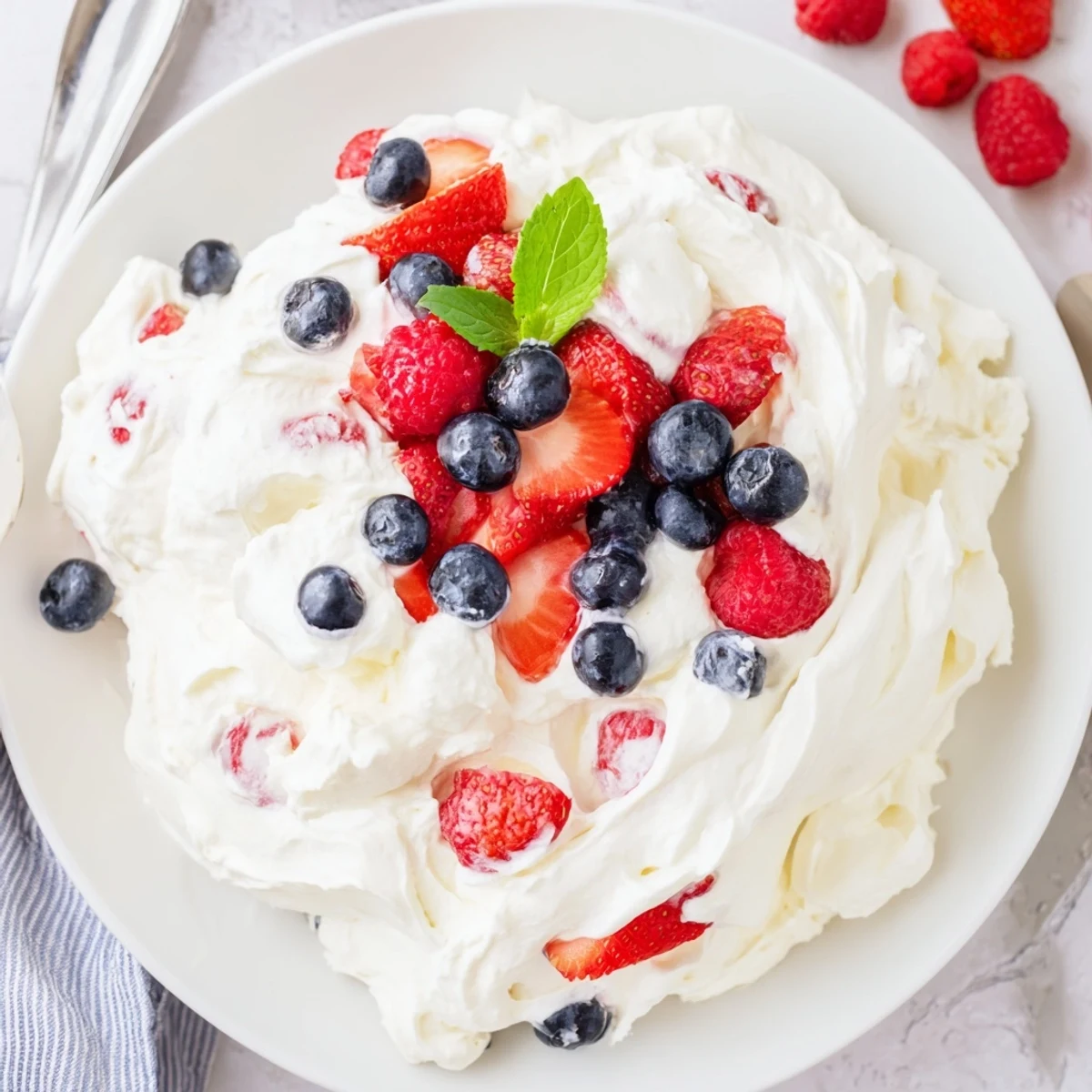 Festive Red White Blue Cheesecake Salad served chilled in a clear glass bowl