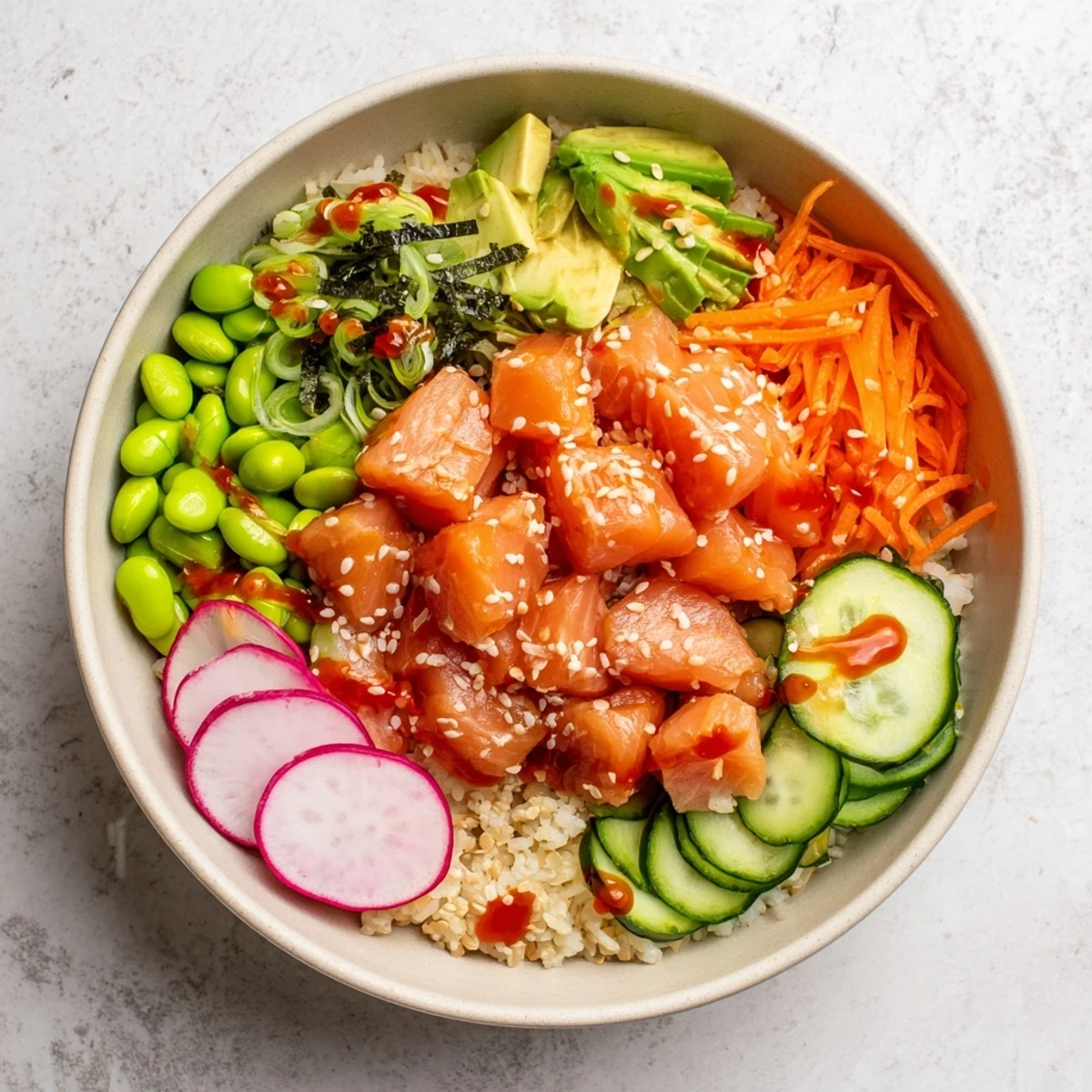 Vibrant salmon and avocado poke bowl arranged with cucumber, edamame, and spicy mayo