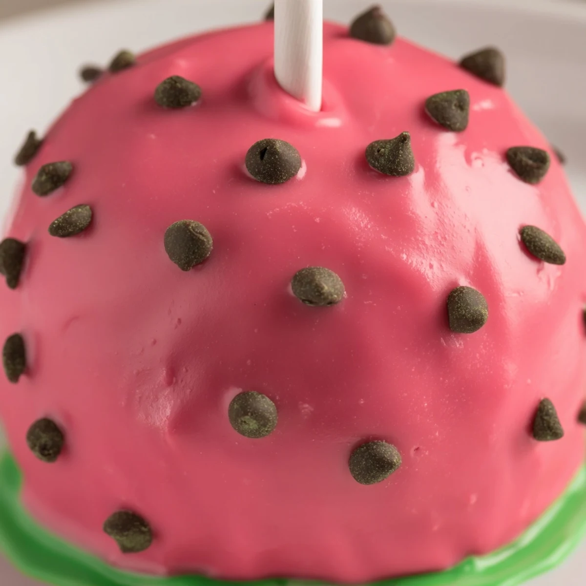 Bite-sized watermelon cake pops arranged on stand showing red candy melt coating and chocolate sprinkles
