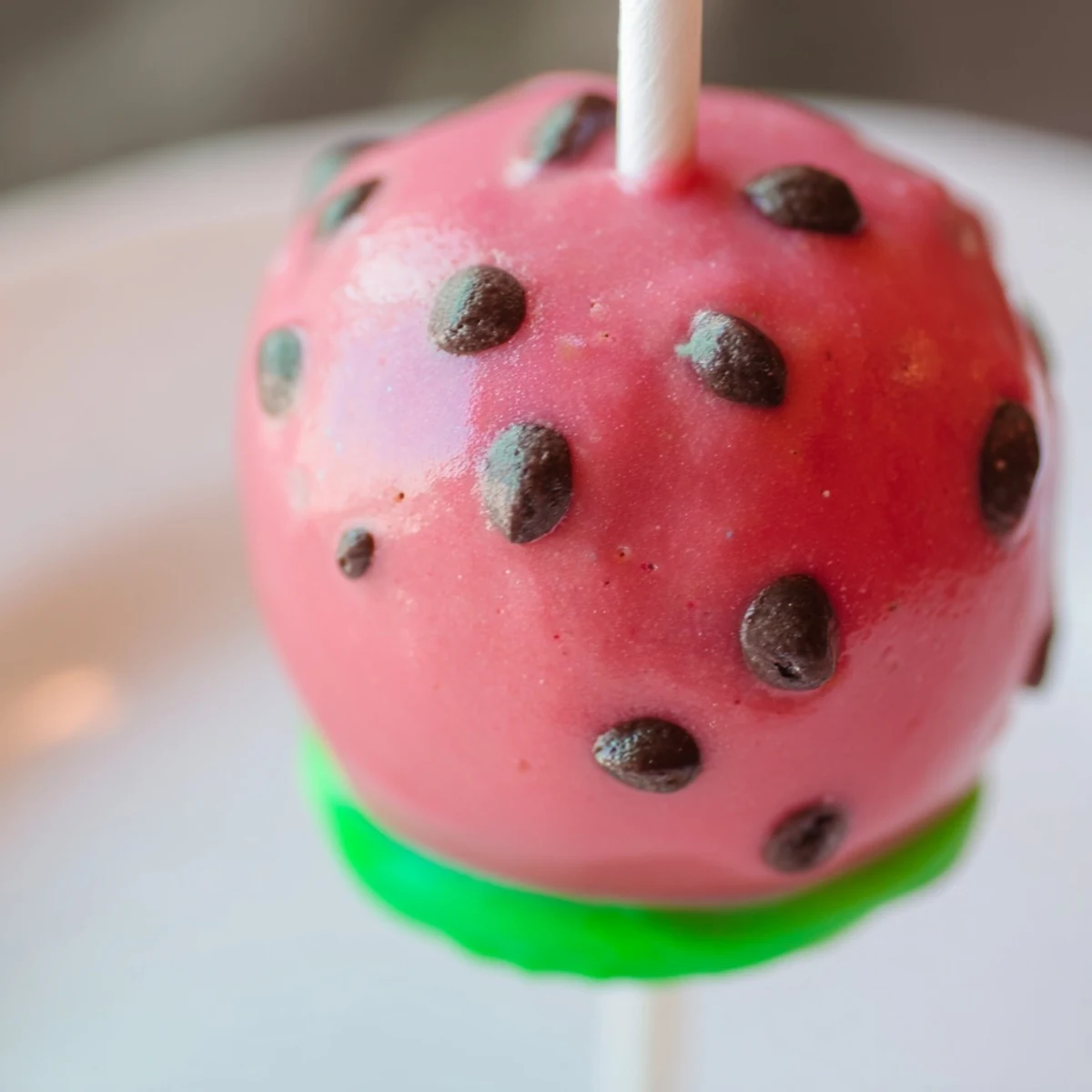Homemade watermelon cake pops displayed with green candy rind edge and chocolate seed details