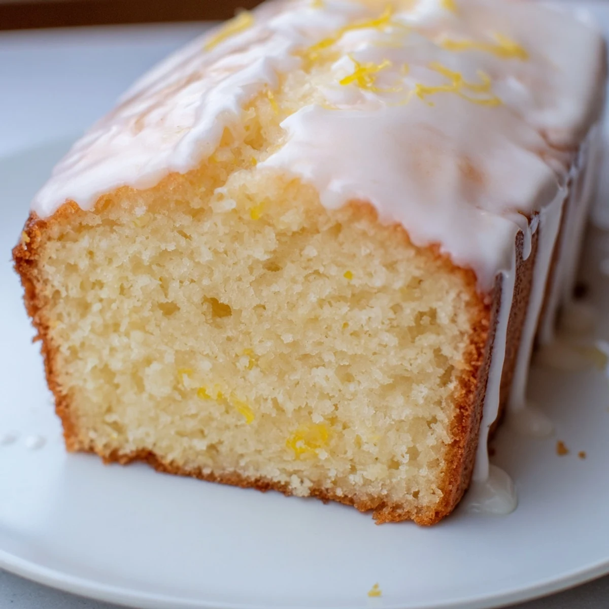 Greek yogurt lemon bread cooling on wire rack with zesty glaze and lemon wedges nearby