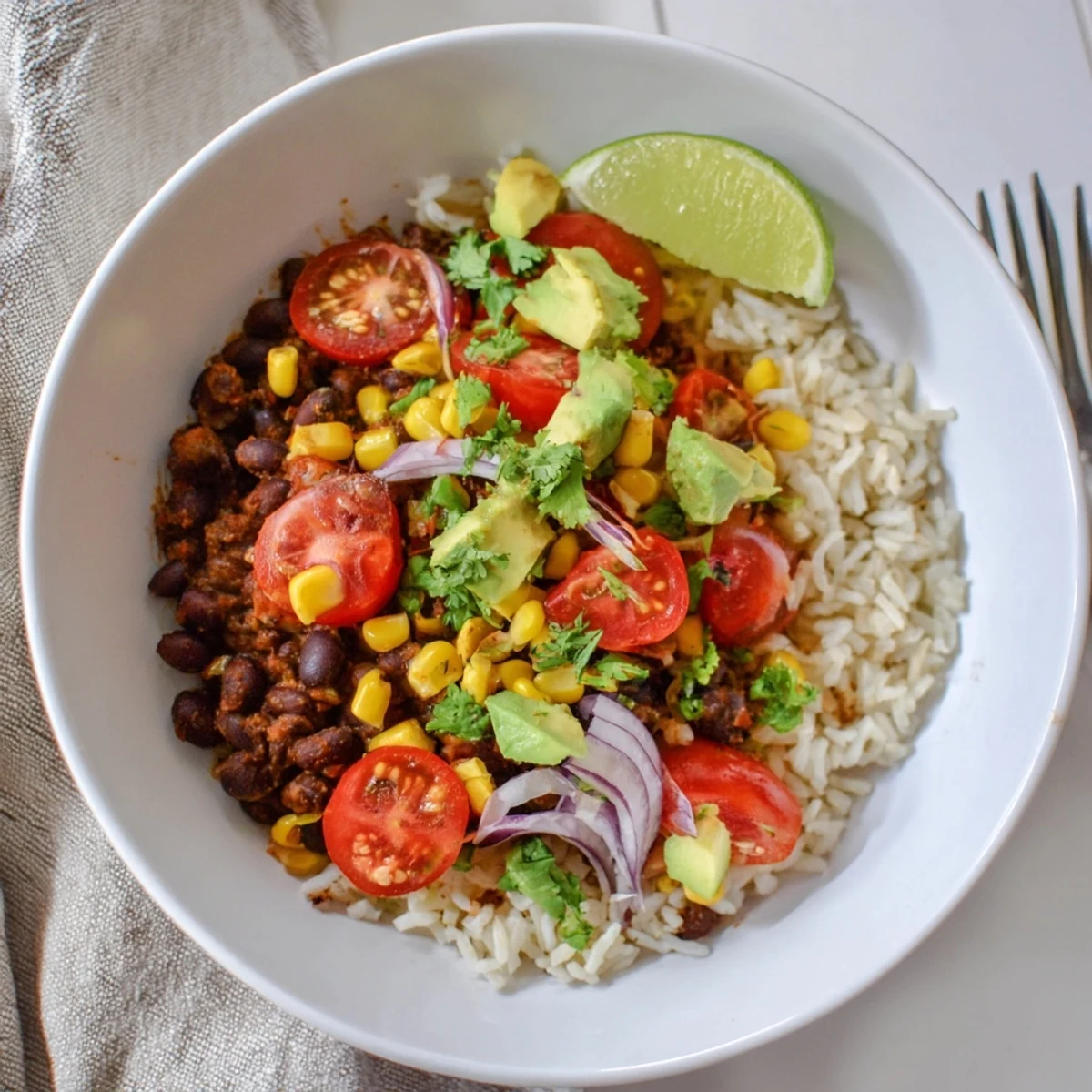 Colorful black bean and rice bowl topped with ripe avocado, fresh cilantro, and juicy tomatoes