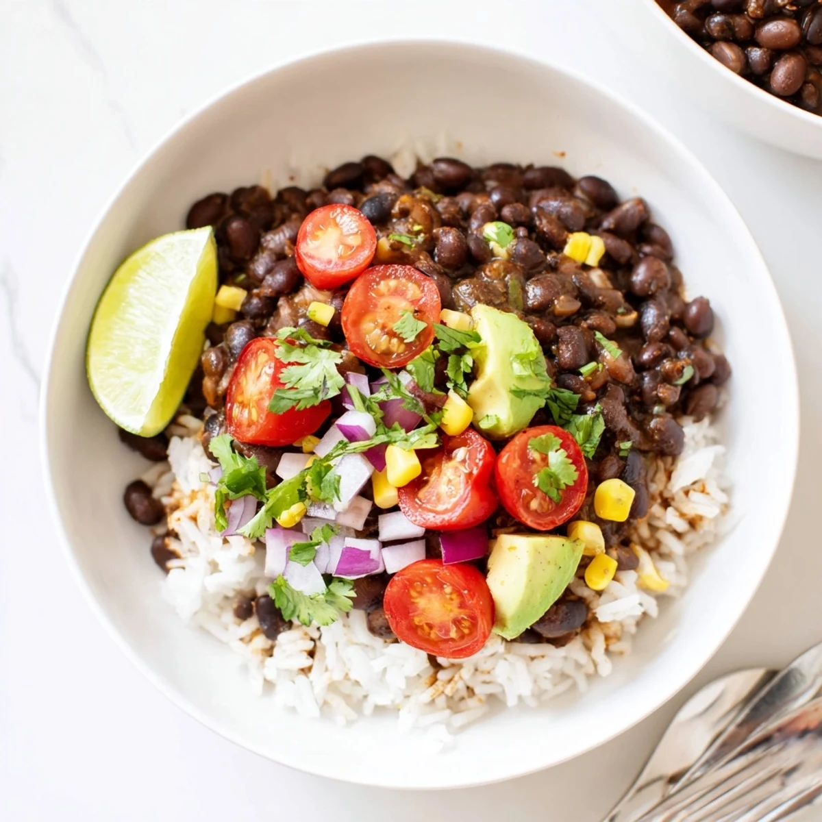 Steaming black bean and rice bowl served with vibrant cherry tomatoes and fragrant seasoned beans