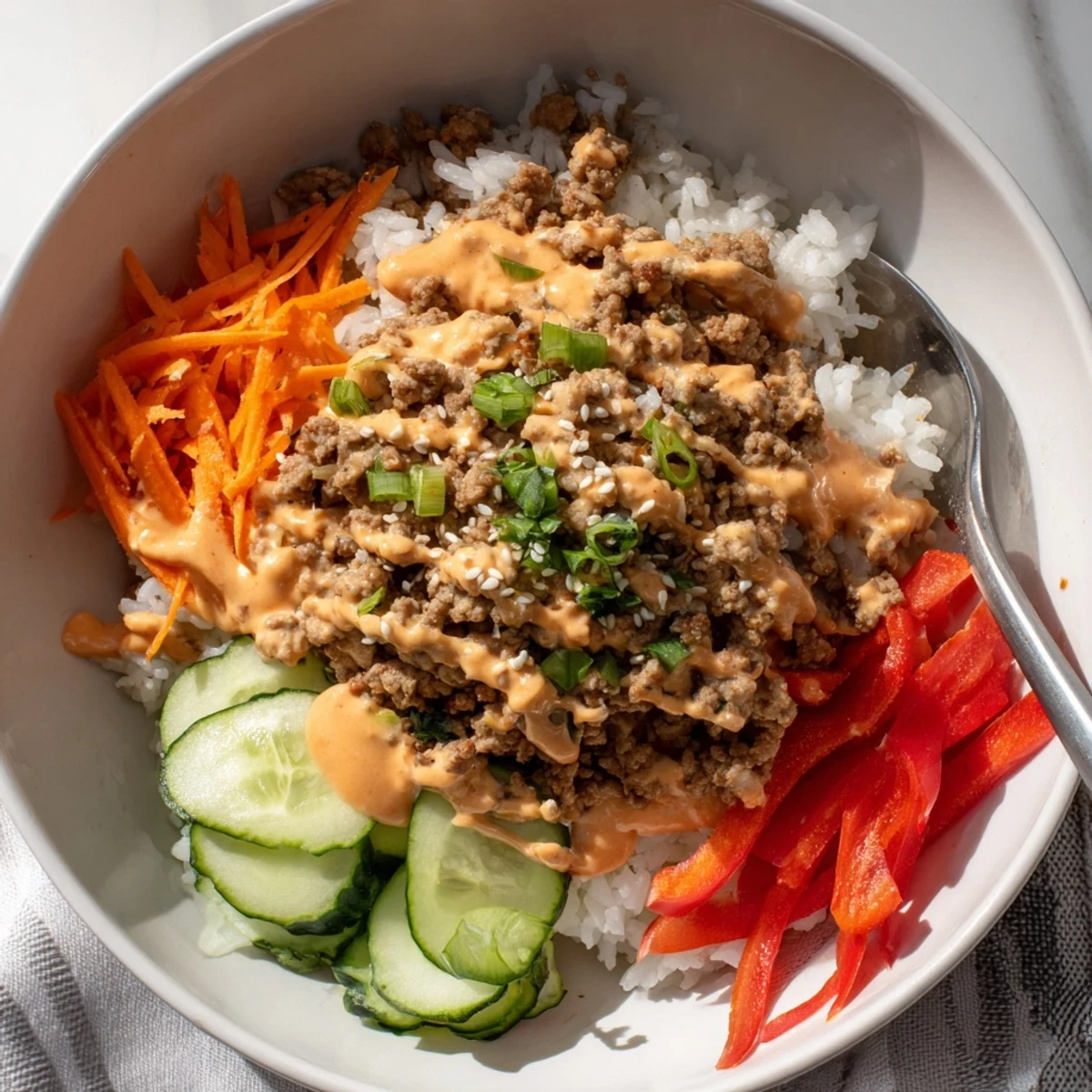 Spicy Bang Bang Sauce cascading over seasoned ground turkey rice bowls with colorful crunchy vegetables.