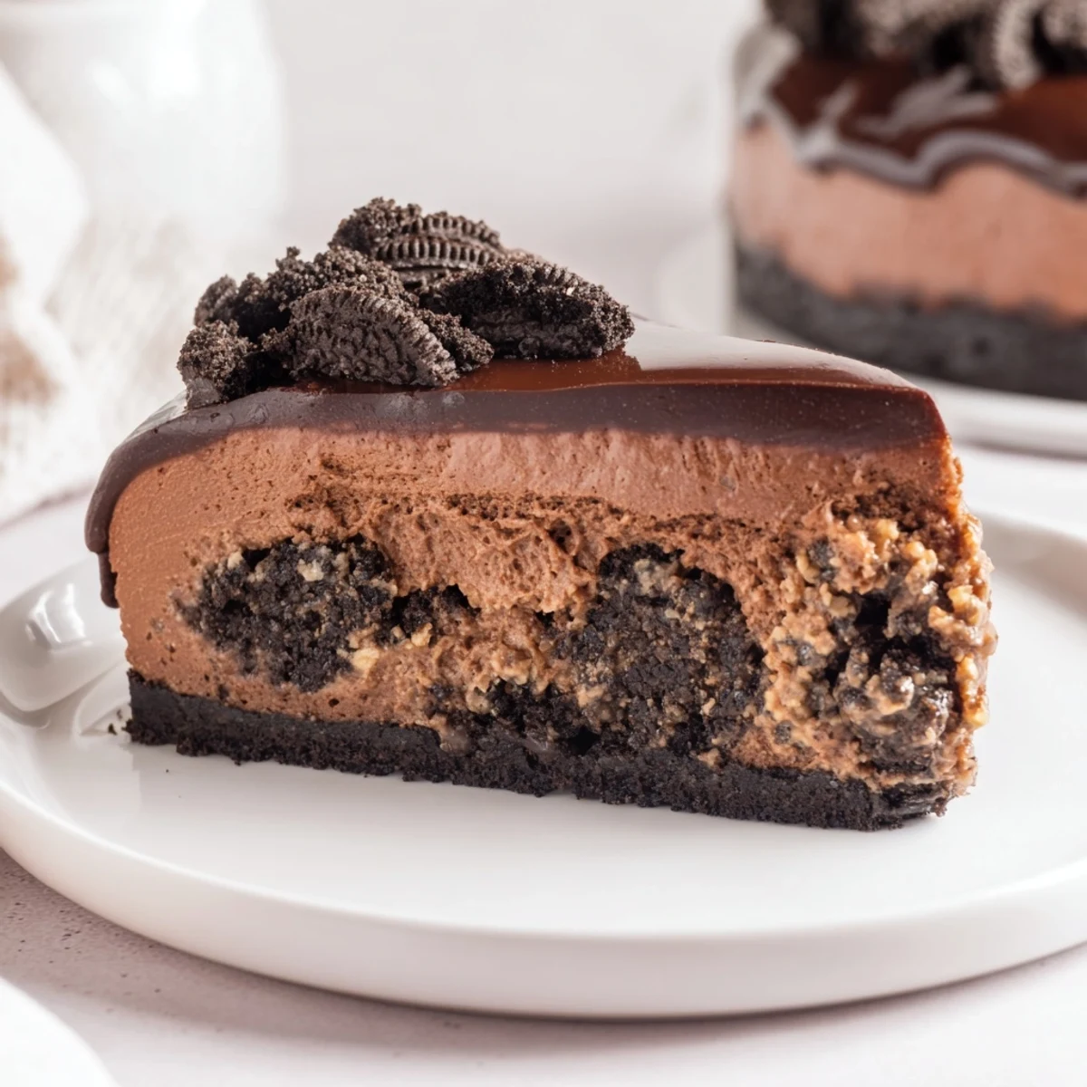 Decadent slice of Oreo chocolate cheesecake showing a crumbly crust and smooth chocolate center.