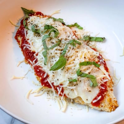 Amazing 15 Minute Keto Chicken Parmesan served on a bed of spiralized zucchini noodles.