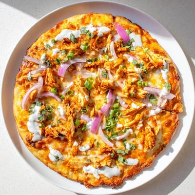 Bold Buffalo Chicken Pizza is sliced and served with extra ranch and celery on the side.
