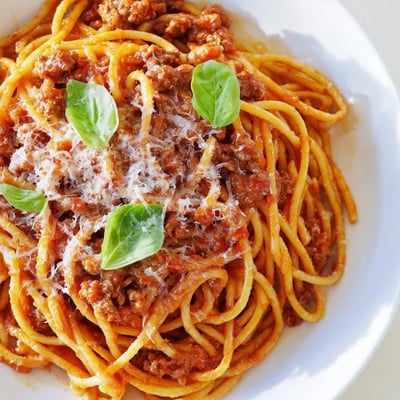A close-up of The Bear Spaghetti reveals a rich, glossy tomato sauce clinging to the pasta.